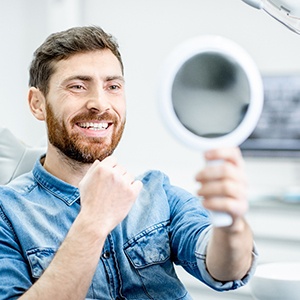 Male dental patient checking smile in a handheld mirror