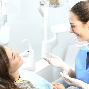 A female patient in the dentist chair talking to her dentist
