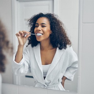 Woman brushing her teeth while in the bathroom    