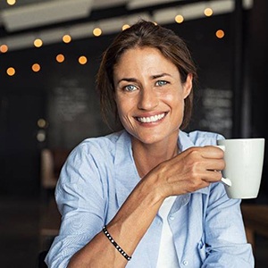 happy woman in a coffee shop holding a white mug