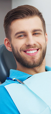 Young man with beard smiling in dental chair