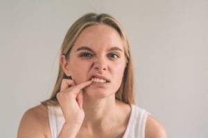 Woman poking at her gums with gum disease in Jacksonville
