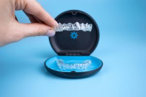 Close up of someone holding an Invisalign tray over its container